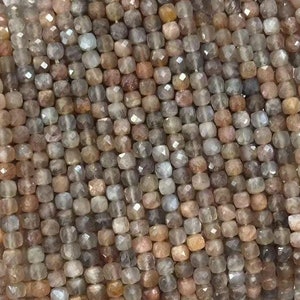 May include: A strand of faceted, square-shaped sunstone beads in shades of brown, pink, and white. The beads are approximately 4mm in size.