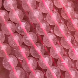 Peut inclure: Un brin de perles de quartz rose. Les perles sont rondes et translucides, avec une légère brillance. Elles sont enfilées sur un cordon élastique transparent.