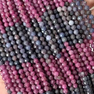 Può includere: Un filo di perline di pietre preziose sfaccettate in tonalità rosa e blu. Le perline sono piccole e di dimensioni uniformi e sono infilate su un filo trasparente.