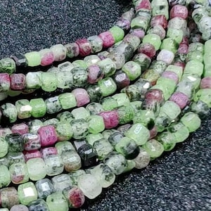 Może przedstawiać: Szereg zielonych i różowych koralików z kamieni szlachetnych, każdy koralik ma kwadratowy kształt. Koraliki są nawleczone na sznurek, tworząc naszyjnik.