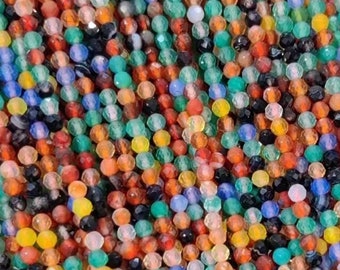 May include: A strand of multi-colored gemstone beads. The beads are faceted and have a variety of colors, including red, orange, yellow, green, blue, and black.