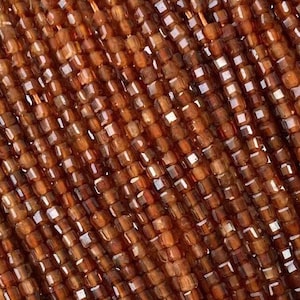 May include: A strand of brown gemstone beads, each bead is a square shape. The beads are strung on a wire and are arranged in a row. The text "棱石 榴石" is visible in the image.