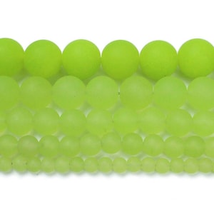 May include: A collection of green frosted glass beads in various sizes. The beads are round and smooth, with a matte finish.