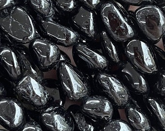 Könnte beinhalten: Eine Schnur aus schwarzen Turmalin-Edelsteinkugeln, jede Kugel ist glatt und abgerundet. Die Kugeln sind in Reihen angeordnet und bilden ein strukturiertes Muster. Der Text "Black Tourmaline" und "黑碧玺" ist im Bild sichtbar.