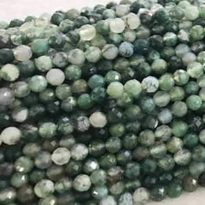 May include: A strand of green moss agate beads. The beads are faceted and have a natural, earthy look.