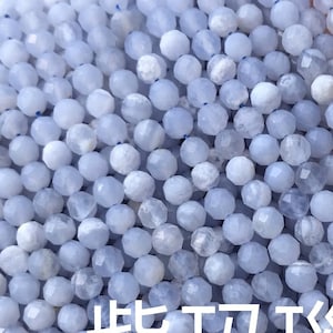 Peut inclure: Gros plan sur des brins de perles de pierres précieuses d'agate Blue Lace bleu clair. Les petites perles à facettes ont un aspect légèrement translucide. Le texte "紫玛瑙 Blue Lace Agate" est inclus.