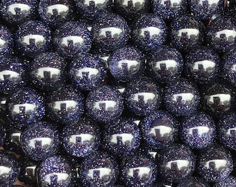 May include: A strand of dark blue round beads with a sparkly, glittery finish. The beads are made of natural stone and have a smooth, polished surface.