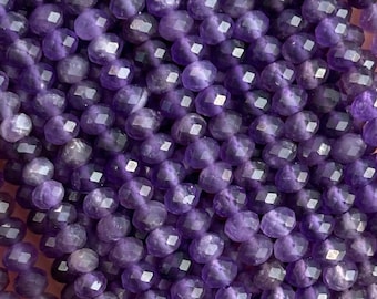 May include: A strand of amethyst gemstone beads, faceted and strung together. The beads are a deep purple color and have a shiny, polished finish.