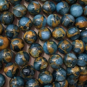 Peut inclure: Un brin de perles de pierres précieuses bleues et brunes. Les perles sont rondes et ont un aspect marbré.