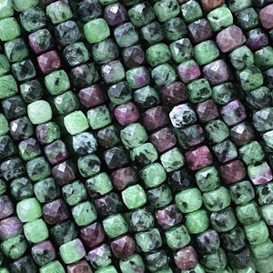 Może przedstawiać: Sznur zielonych i czerwonych koralików z kamieni szlachetnych. Koraliki są fasetowane i mają kwadratowy kształt.