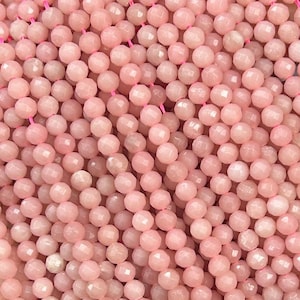 Puede incluir: Una hebra de cuentas de piedras preciosas rosas, facetadas y redondas, enhebradas en un hilo transparente. Las cuentas son uniformes en tamaño y color, creando un aspecto liso y elegante.