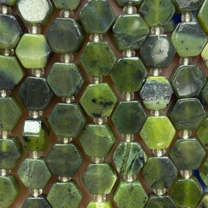 May include: Strands of green hexagonal beads. The beads have a mix of light and dark green hues, with some showing black veining. The beads are strung together with a clear, thin cord. The beads are faceted, giving them a polished appearance.