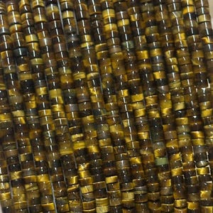 May include: Close-up of strands of tiger's eye beads. The beads are small, cylindrical, and display a mix of golden brown and dark brown hues. The polished beads are strung together, ideal for crafting jewellery.