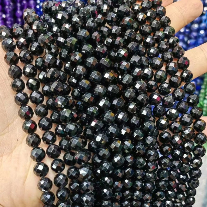 Peut inclure: Un brin de perles de pierres pr&eacute;cieuses facett&eacute;es noires. Les perles sont rondes et ont une surface brillante et r&eacute;fl&eacute;chissante.