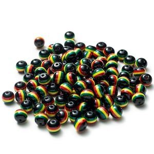 Puede incluir: Un montón grande de cuentas redondas de plástico con rayas negras, rojas, amarillas y verdes. Las cuentas tienen un diámetro de aproximadamente 1 cm.