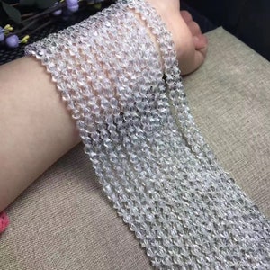 May include: A strand of clear crystal beads, faceted and strung together. The beads are small and uniform in size, creating a delicate and elegant look.