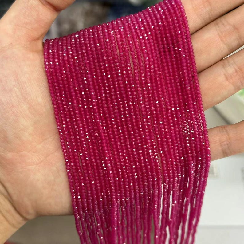 May include: A strand of pink ruby beads, faceted and strung on a thin thread. The beads are small and uniform in size, creating a delicate and elegant look.