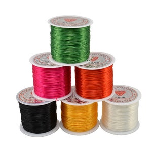 May include: Six spools of elastic string in different colors: green, pink, orange, black, yellow, and white. Each spool is labeled with Japanese text and a diamond symbol.