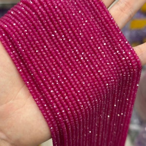 May include: A strand of pink faceted gemstone beads. The beads are small and uniform in size and shape. The strand is long and appears to be made of many individual beads.
