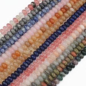 K&ouml;nnte beinhalten: Eine Sammlung runder, glatter Edelsteinperlen in verschiedenen Farben, darunter Blau, Rosa, Gr&uuml;n, Braun und Grau. Die Perlen sind in Reihen angeordnet und bilden ein optisch ansprechendes Muster.