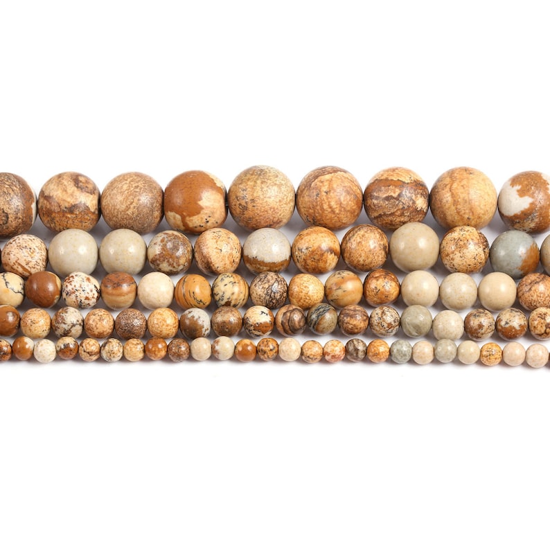 May include: A strand of brown and beige gemstone beads of varying sizes. The beads are round and have a mottled pattern.