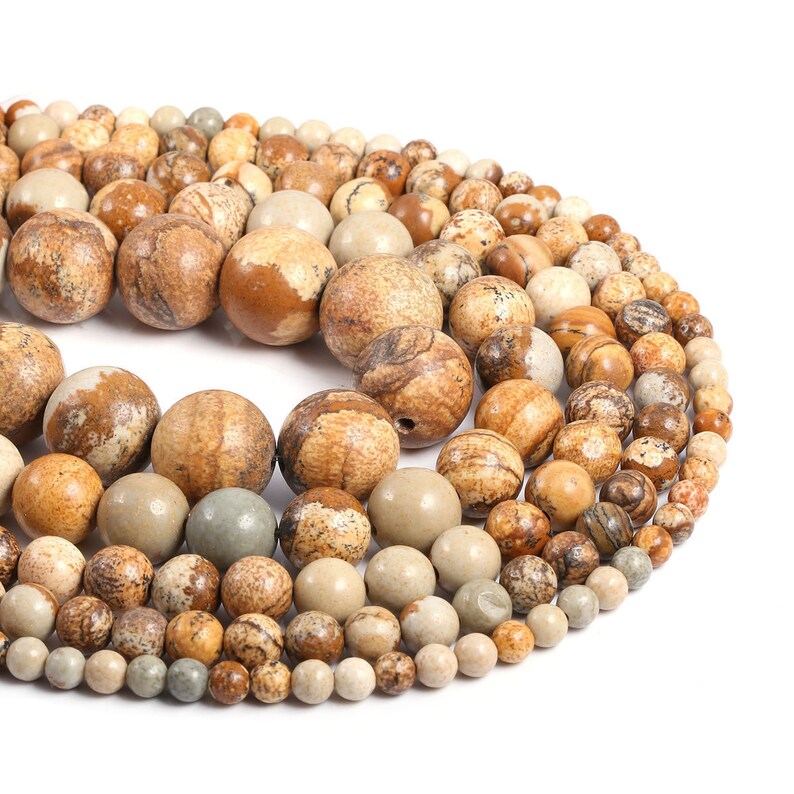 May include: A strand of brown, beige, and gray gemstone beads. The beads are round and have a speckled pattern.