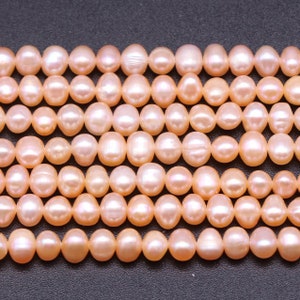 May include: A strand of pale pink freshwater pearls. The pearls are round and smooth, with a slight iridescent sheen.