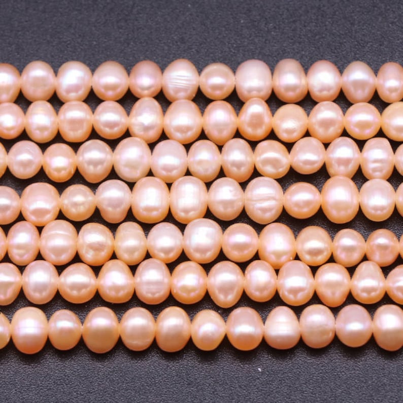 May include: A strand of pale pink freshwater pearls. The pearls are round and smooth, with a slight iridescent sheen.
