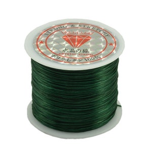 May include: A spool of dark green elastic string, labeled "Strong & Stretchy" and "Crystal String 100%" in Japanese and English.