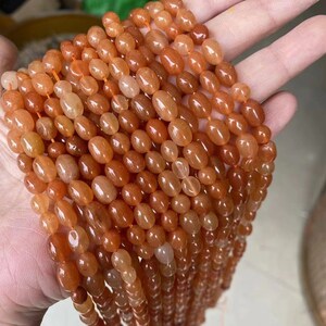 Puede incluir: Una hebra de cuentas de cornalina naranja, cada cuenta es de forma ovalada y lisa. Las cuentas est&aacute;n enhebradas en un hilo transparente y est&aacute;n listas para ser utilizadas para la elaboraci&oacute;n de joyas.