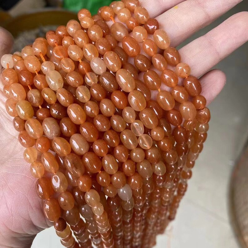 Puede incluir: Una hebra de cuentas de cornalina naranja, cada cuenta es de forma ovalada y lisa. Las cuentas est&aacute;n enhebradas en un hilo transparente y est&aacute;n listas para ser utilizadas para la elaboraci&oacute;n de joyas.
