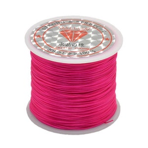 May include: A spool of bright pink elastic string, labeled "Strong & Stretchy" and "Crystal String 100%".