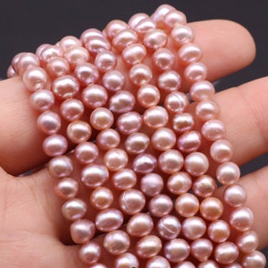 May include: A strand of pink freshwater pearls. The pearls are round and have a smooth, iridescent finish.