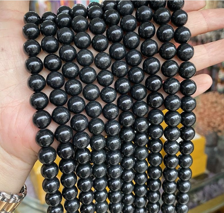 May include: A strand of black gemstone beads. The beads are round and smooth, and they have a slightly shiny finish.
