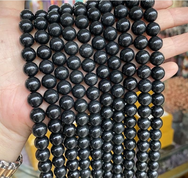 May include: A strand of black gemstone beads. The beads are round and smooth, and they have a slightly shiny finish.