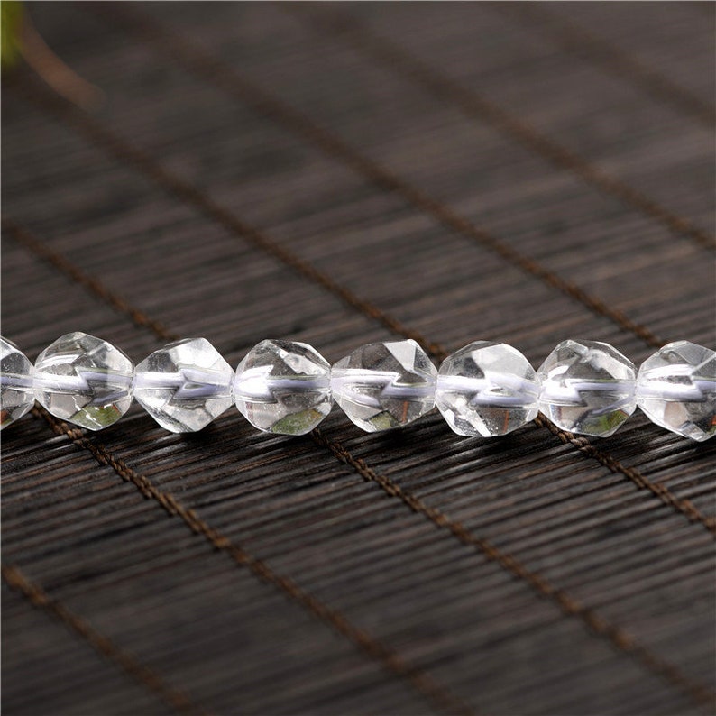 May include: A strand of clear faceted crystal beads. The beads are round and have a smooth, polished finish.