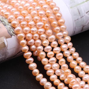 May include: A strand of pale pink freshwater pearls. The pearls are round and smooth, and they are strung on a white thread. The pearls are arranged in a row, and they are all the same size.