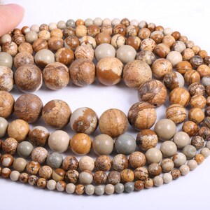 May include: A strand of brown, beige, and gray gemstone beads. The beads are round and have a natural, marbled pattern.
