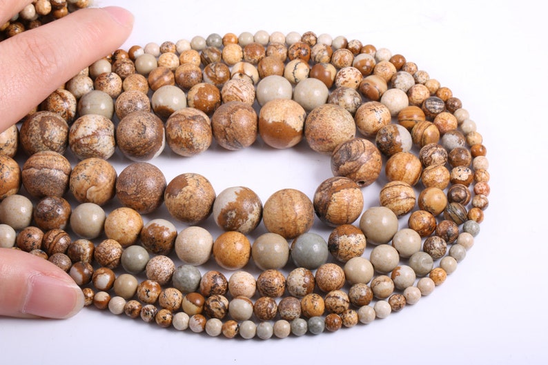 May include: A strand of brown, beige, and gray gemstone beads. The beads are round and have a natural, marbled pattern.