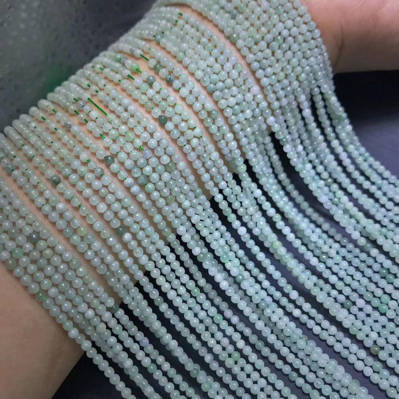 Puede incluir: Hebras de peque&ntilde;as cuentas redondas de color verde p&aacute;lido. Las cuentas est&aacute;n ensartadas, creando m&uacute;ltiples l&iacute;neas de la misma joyer&iacute;a. Las cuentas tienen una ligera variaci&oacute;n de color, algunas parecen m&aacute;s opacas que otras. Las cuentas probablemente se utilizan para la fabricaci&oacute;n de joyas.