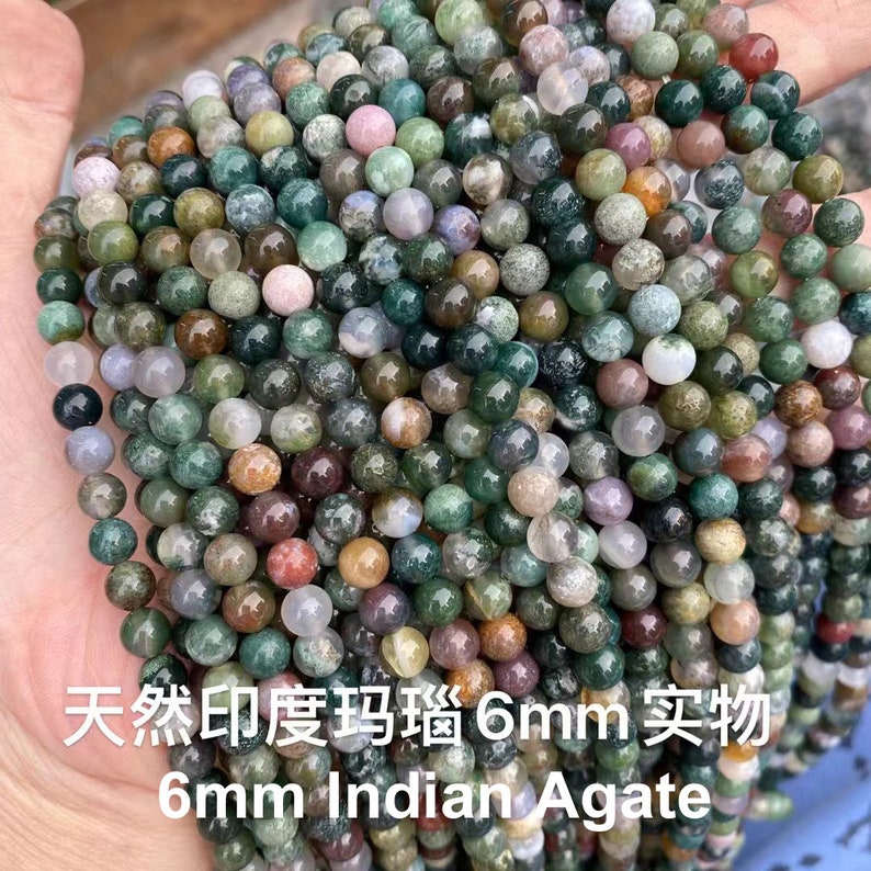 May include: A strand of 6mm Indian agate beads in various shades of green, brown, and white. The beads are round and have a natural, polished finish.  "Natural 印度瑪瑙 6mm 实物 6mm Indian Agate" is written in the image.