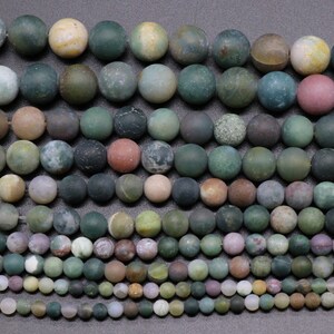 May include: A collection of round, green, brown, and white agate beads. The beads are various sizes and have a mottled, natural appearance.