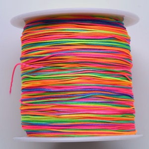 Puede incluir: Una bobina de hilo de ne&oacute;n de colores, enrollada apretadamente en un patr&oacute;n de arco&iacute;ris. El hilo es perfecto para manualidades, hacer joyas y otros proyectos de bricolaje.
