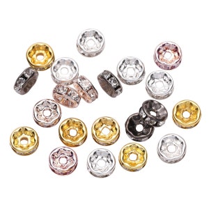 Pu&ograve; includere: Assortimento di piccole capsule per perline rotonde in metallo con accenti di strass trasparenti. Le capsule per perline sono di vari colori, tra cui oro, argento, nero e oro rosa.