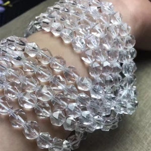 May include: A strand of clear faceted crystal beads. The beads are round and have a smooth, polished finish. The beads are strung on a clear thread.