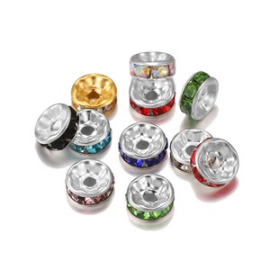 Pu&ograve; includere: Assortimento di cappucci per perline color argento con una variet&agrave; di strass colorati. I cappucci per perline sono rotondi e hanno un piccolo foro al centro. Gli strass sono di colore rosso, verde, blu, nero, rosa e trasparente.
