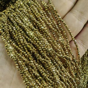 Puede incluir: Una hebra de cuentas de pirita dorada, también conocida como oro de los tontos, con un acabado facetado y brillante. Las cuentas son pequeñas y uniformes en tamaño, creando un aspecto delicado y elegante.