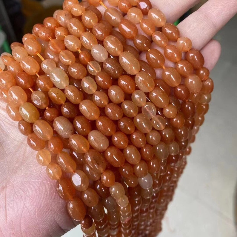 Puede incluir: Una hebra de cuentas de cornalina naranja, cada cuenta tiene forma ovalada y est&aacute; pulida hasta quedar lisa. Las cuentas est&aacute;n enhebradas en un hilo fino y est&aacute;n listas para ser utilizadas en la elaboraci&oacute;n de joyas.