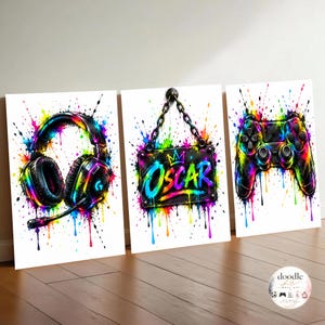 Puede incluir: Un conjunto de tres láminas decorativas verticales que muestran unos auriculares de juego, un cartel rectangular colgante con el nombre Oscar y un icono de corona, y un mando de juego. Cada elemento tiene un estilo de salpicaduras de pintura.