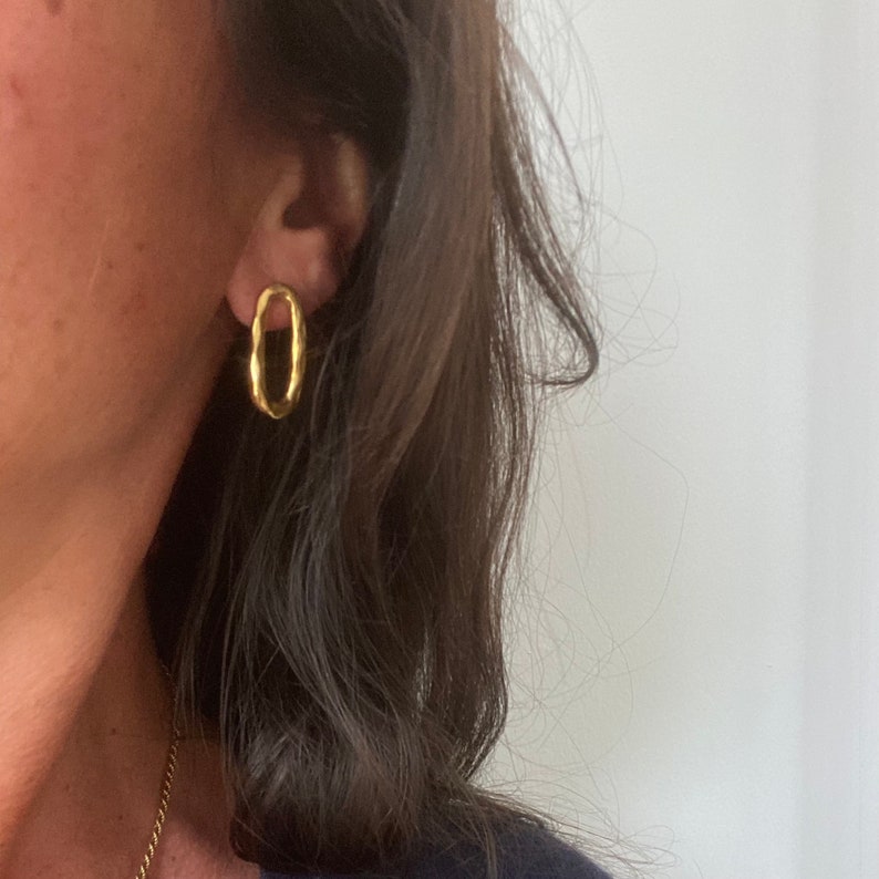 May include: A pair of gold oval hoop earrings. The earrings are simple and elegant, and they would be a great addition to any jewellery collection.